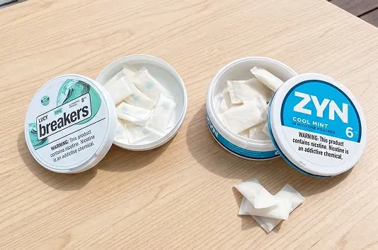 Open cans of LUCY Breakers and ZYN Cool Mint with pouches, including a Breakers pouch with a visible flavor capsule