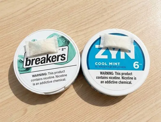 Closed LUCY Breakers and ZYN Cool Mint cans with a nicotine pouch resting on each lid