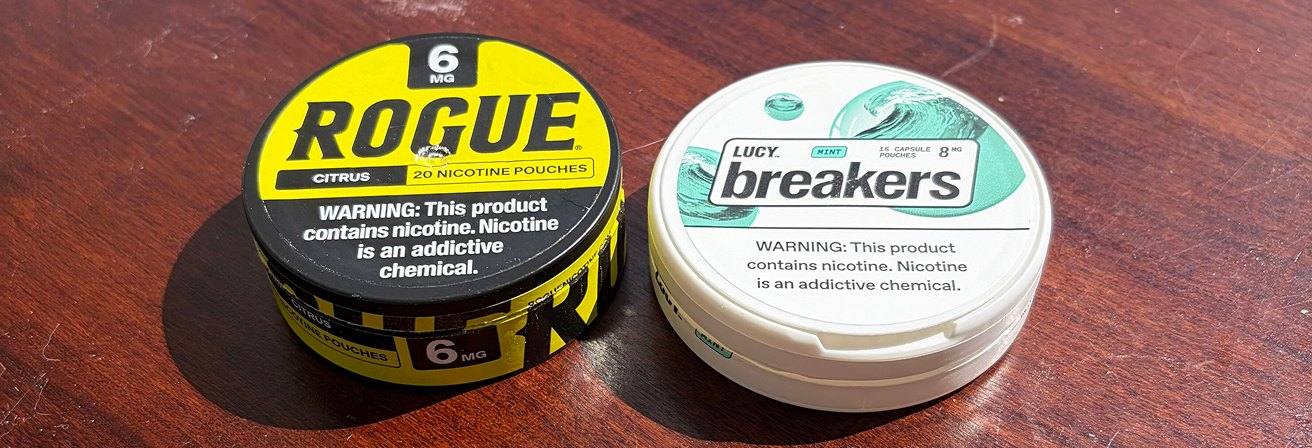 Rogue Citrus and LUCY Breakers Mint nicotine pouch cans on a wooden table
